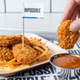 Tray of Impossible Chicken Nuggets and fries, with one nugget being dipped into sauce